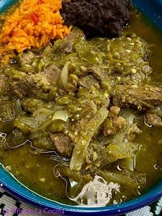 a blue bowl filled with meat and vegetables next to rice on top of a table