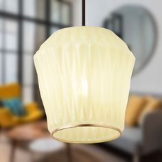 a white light hanging from a ceiling in a living room next to a yellow chair