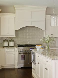 a kitchen with white cabinets and marble counter tops