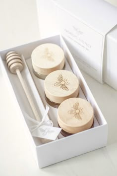 three wooden spoons in a white box next to a honey dipper and fork