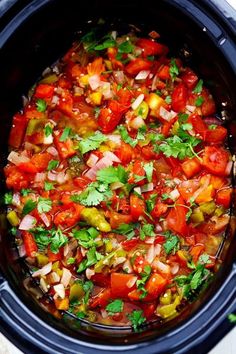 a crock pot filled with lots of different types of vegetables and garnishes