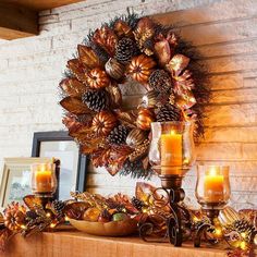 a mantle with candles, pine cones and other decorations