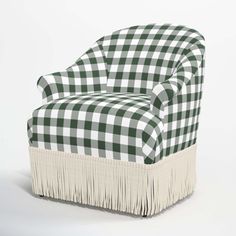 a green and white checkered chair with fringes on the legs, sitting in front of a white background