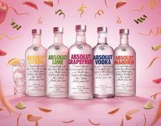 three bottles of absolut vodka surrounded by confetti and streamers on a pink background