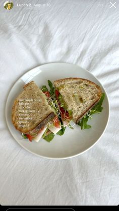 a white plate topped with a cut in half sandwich on top of a white table cloth