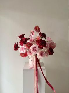 a white vase with red and pink flowers in it