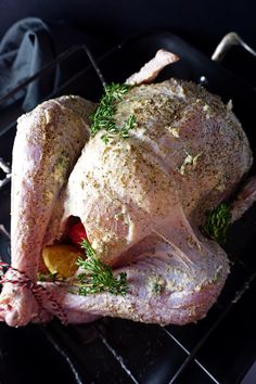 a whole chicken sitting on top of a metal rack with herbs and spices around it