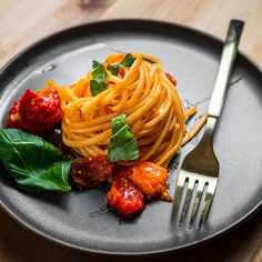 a plate with spaghetti, meatballs and spinach on it next to a fork