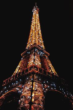 the eiffel tower lit up at night with lights on it's sides