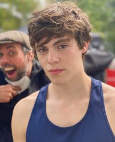 a young man in blue tank top standing next to an older man with his mouth open