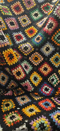 a multicolored quilt is laying on top of a chair with a black background