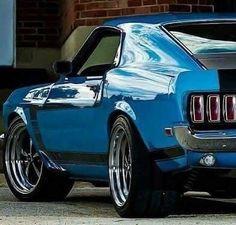 a blue mustang parked in front of a brick building