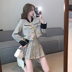 a woman taking a selfie in front of a mirror wearing a skirt and jacket