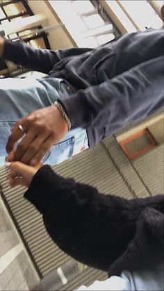 a man sitting on an escalator holding his hand out to someone with their foot in the air