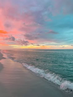 an ocean beach with waves coming in to shore and the sun setting over the water