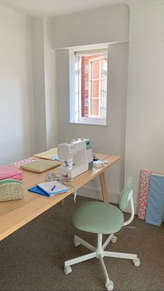 a sewing machine sitting on top of a wooden table next to a chair and window