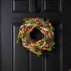 a wreath with carrots and green leaves hanging on a door