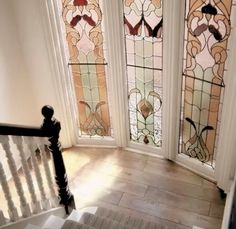 the stairs lead up to three stained glass windows in this home's entryway