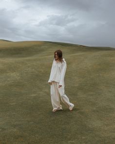 a woman walking across a lush green field