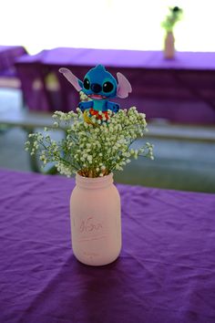 a vase filled with baby's breath flowers on top of a purple table cloth