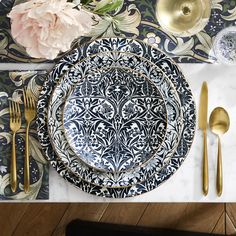 the table is set with black and white plates, silverware, and gold utensils