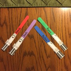 four different colored plastic blades with name tags on them sitting on a wooden table next to a green chair