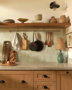 a kitchen counter with pots and pans hanging on the wall above it, along with other cooking utensils