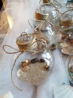 several glass ornaments with shells in them on a white table cloth and some twine