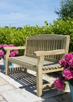 a wooden bench sitting next to pink flowers