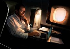 a man is sitting in an airplane and working on his laptop while looking at the screen