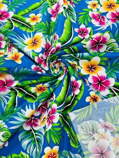 the fabric has flowers on it and is blue with pink, yellow and green leaves