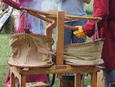 two people standing next to each other in front of a wooden chair with bags on it