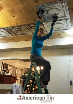 a woman standing on top of a ladder in front of a christmas tree with lights