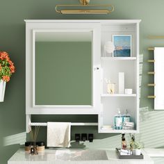 a bathroom with green walls, white cabinets and flowers on the sink counter top in front of it