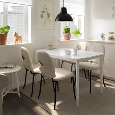 a white table and chairs in a small room with potted plants on the window sill