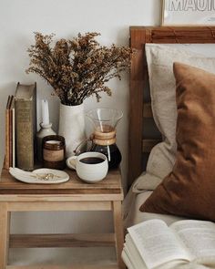 a table with books, coffee pot and vase on it next to an open book