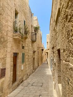 an alley way with stone buildings and plants on the balconies