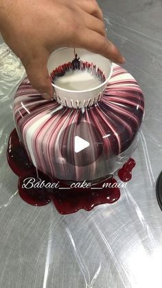 someone is decorating a cake with red and white icing