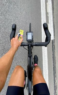 a person riding a bike with their feet on the handlebars holding a cell phone