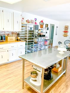 a kitchen with white cabinets and stainless steel counter tops, including an island in the center