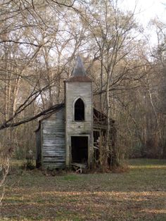 an old run down church in the middle of a forest with no leaves on it