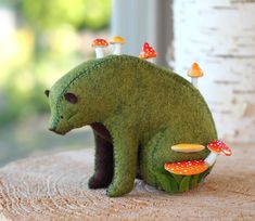 a stuffed bear sitting on top of a table next to mushrooms and mushrooms growing out of it