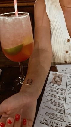 a woman sitting at a table with a drink in front of her and a menu behind her