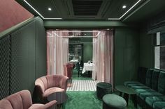 a living room with green walls and pink velvet sofas in the corner, along with other furniture