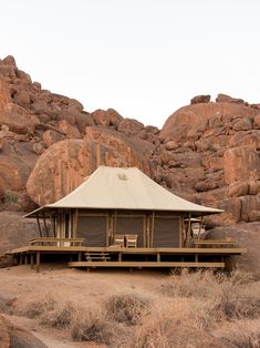 a large tent in the middle of some desert with rocks and grass on either side