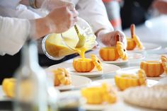 someone is pouring orange juice on small pieces of fruit