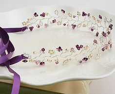 a white plate topped with a purple ribbon and flowered headband on top of a table