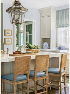 a kitchen island with four chairs and a chandelier hanging from it's ceiling