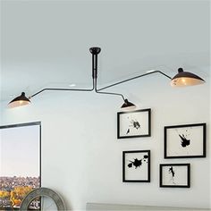 three lights hanging from the ceiling in a room with white walls and pictures on the wall