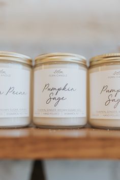 three jars of candles sitting on top of a wooden table